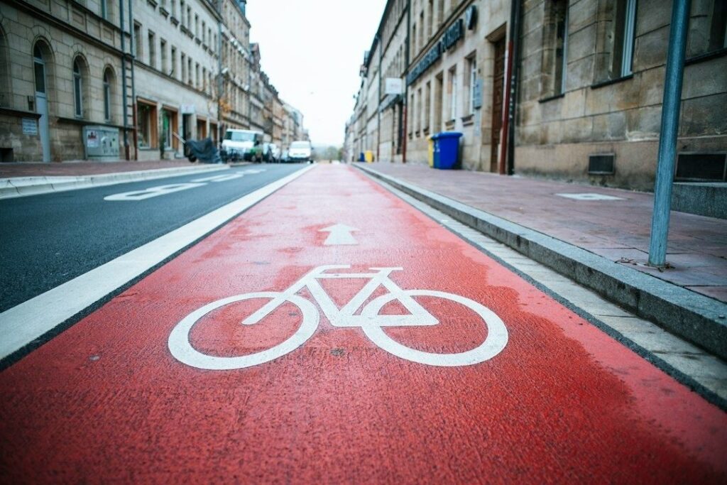 Rood fietspad door een stedelijke straat met gebouwen en verkeer